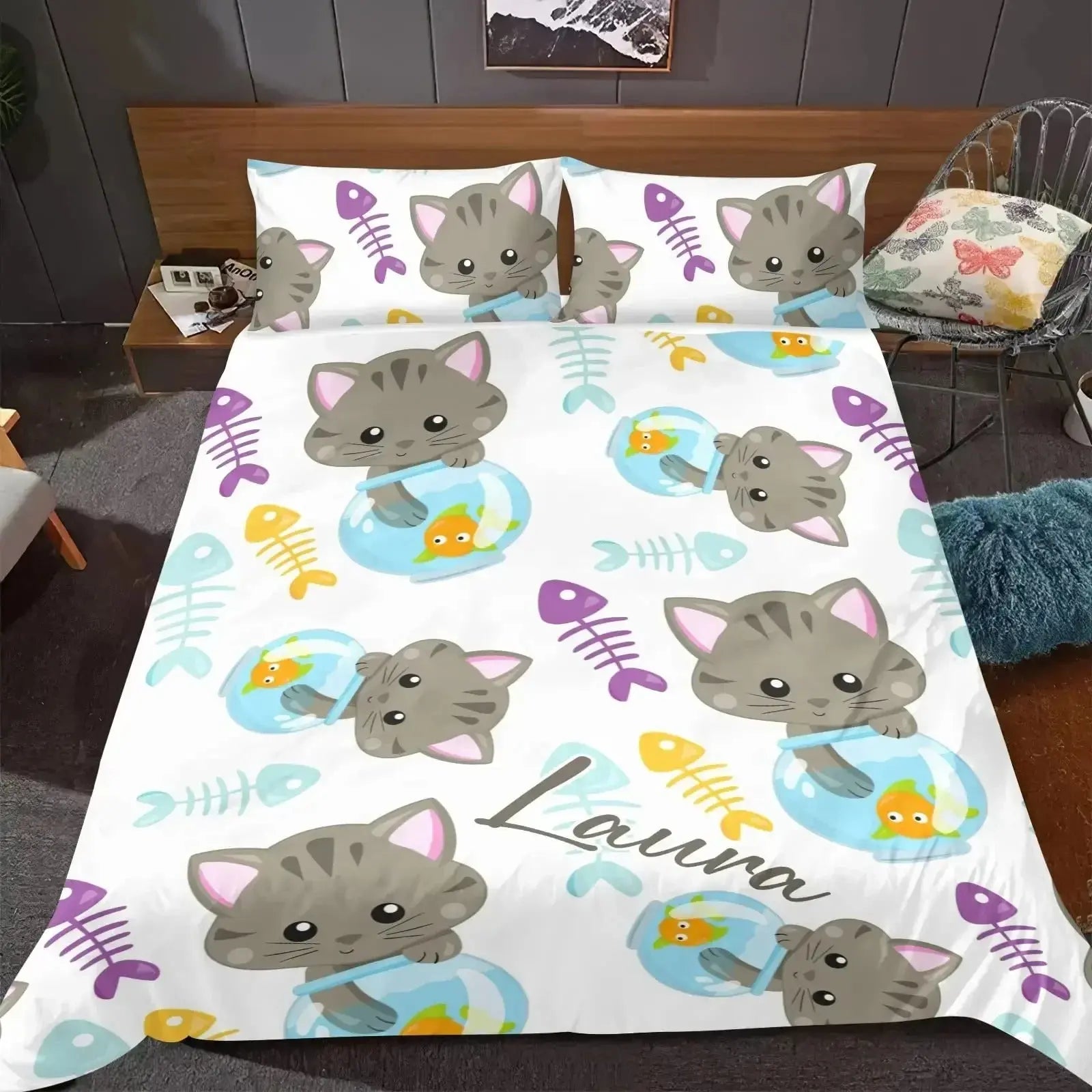 Bedding set with cartoon cat design and 'Laura' branding on a bed.
