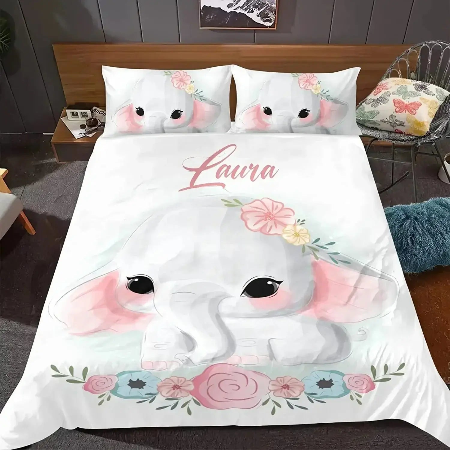 Bedding set with cartoon elephant design and 'Laura' text on a bed in a bedroom setting.