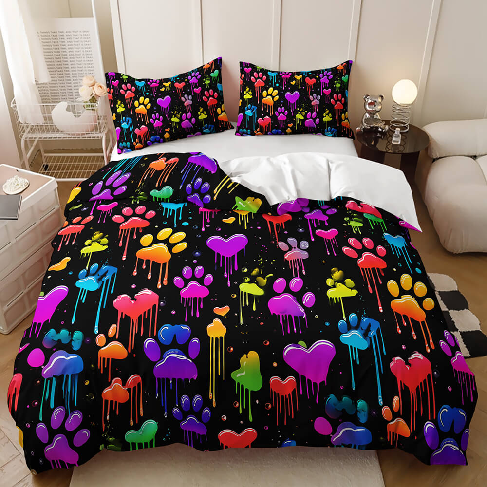 A bed dressed in a black duvet cover and matching pillowcases featuring a vibrant, multicolored graffiti-style print of dripping hearts, paw prints, and small dots, styled in a bedroom setting.