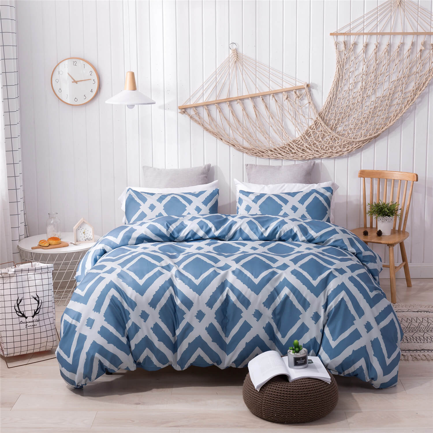 A bed dressed in a blue and white geometric patterned bedding set, styled in a bright, modern bedroom