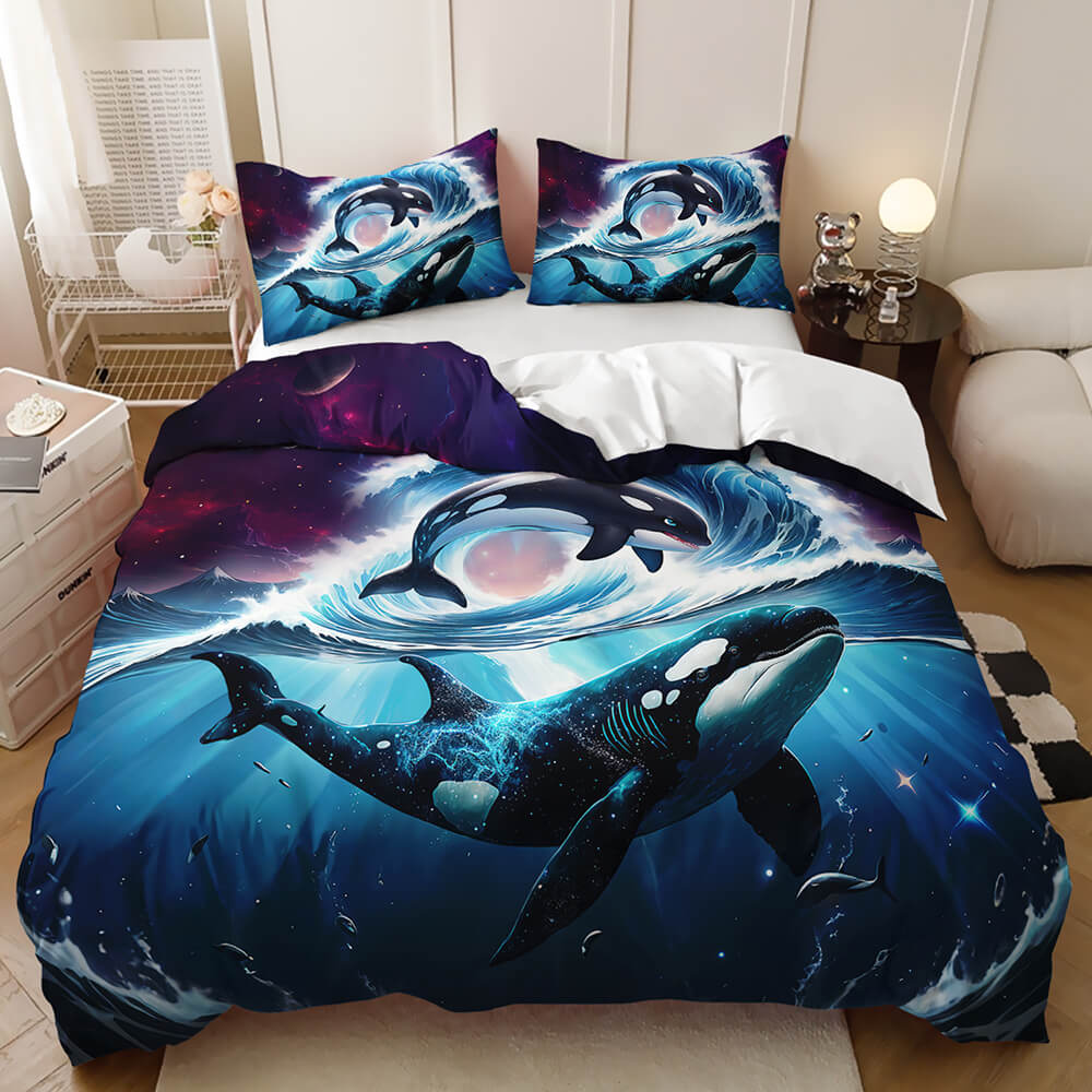 A bedding set featuring a dramatic space-orca print, shown on a made bed in a styled bedroom setting. The duvet cover and two matching pillowcases display a large blue and black orca swimming through deep ocean waves with a galaxy-like purple and pink sky background.