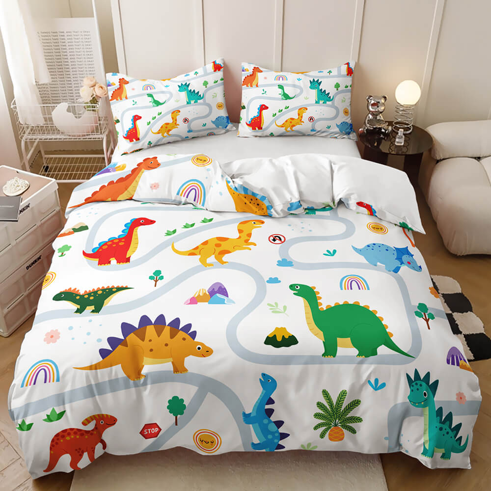 A colorful dinosaur-themed bedding set on a bed in a styled bedroom. The set includes a white duvet cover and matching pillowcases printed with playful cartoon dinosaurs, rainbow motifs, and winding blue path lines.