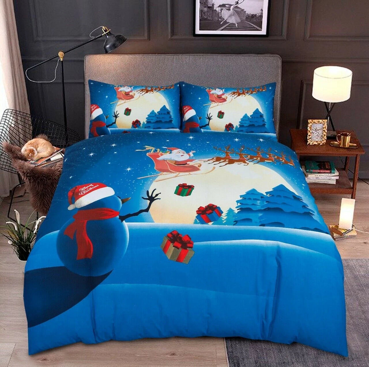 A festive Christmas-themed bedding set featuring a duvet cover and two matching pillowcases with a vibrant print of Santa Claus, a snowman, reindeer, and snowy mountains under a full moon, styled in a bedroom setting.