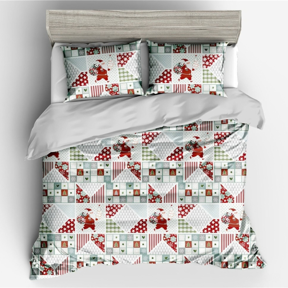 A bedding set featuring a quilt and two matching pillowcases with a patchwork quilt pattern of Santa Claus, red and white polka dots, stripes, and geometric designs, styled on a bed with a gray headboard.