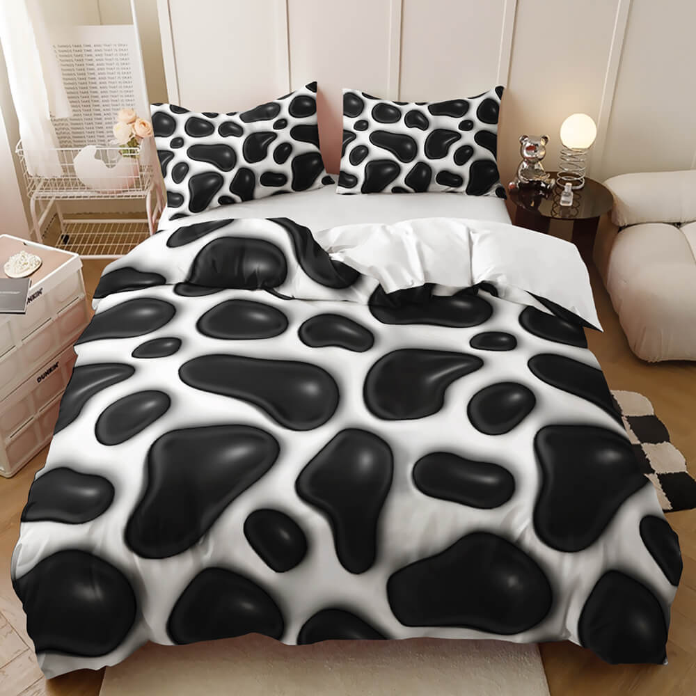 A bed dressed in a black and white cow-print bedding set