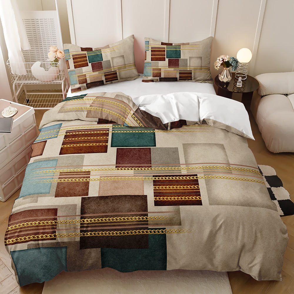 A bed dressed in a patchwork quilt set with geometric blocks in beige, brown, teal, and gold, styled in a modern bedroom setting