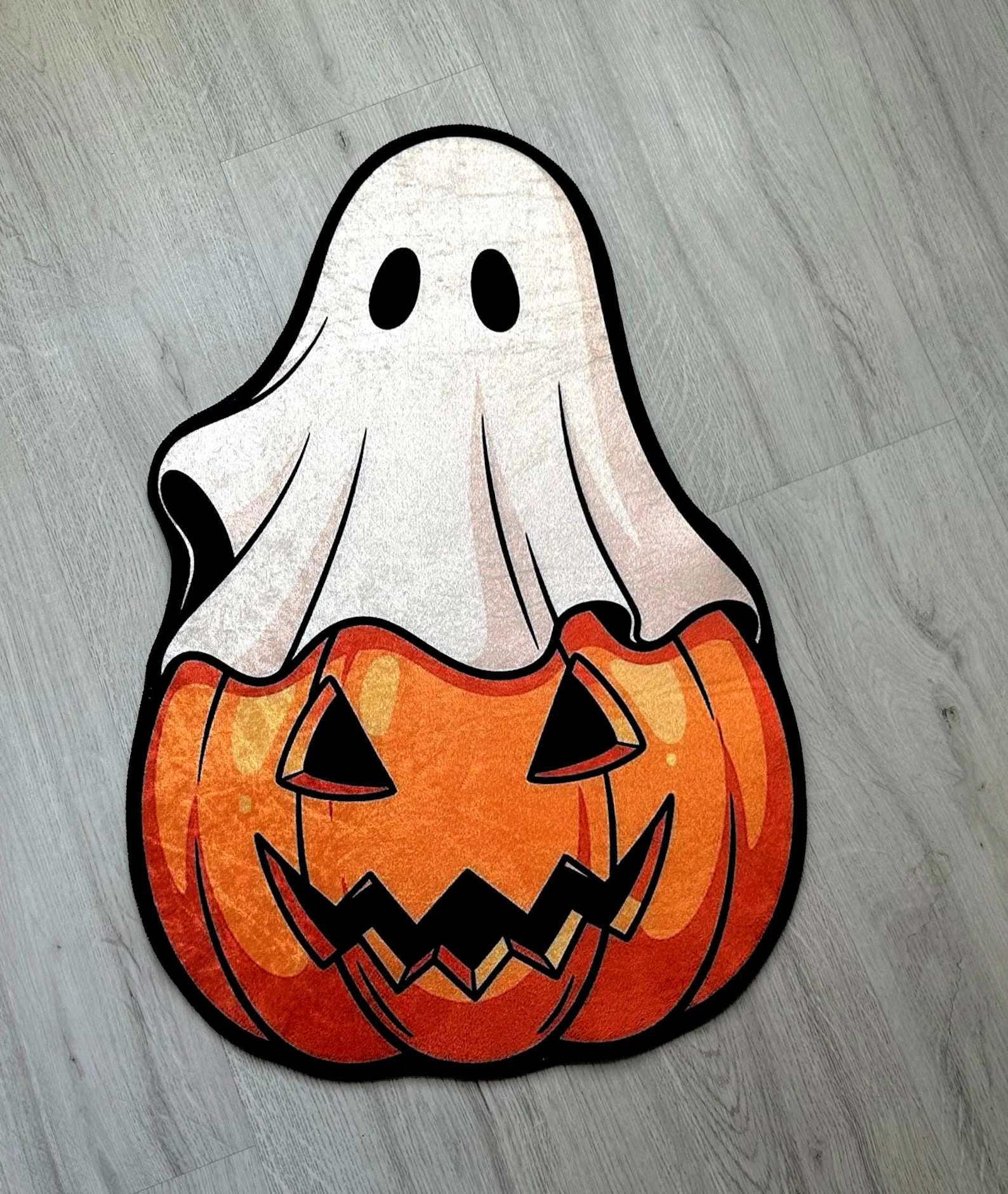 Halloween ghost figurine on a smiling jack-o’-lantern pumpkin