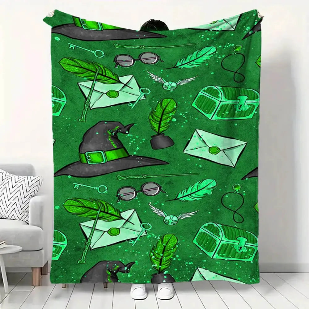 Green blanket with witch-themed design featuring a hat, broomstick, and cauldron on a white floor