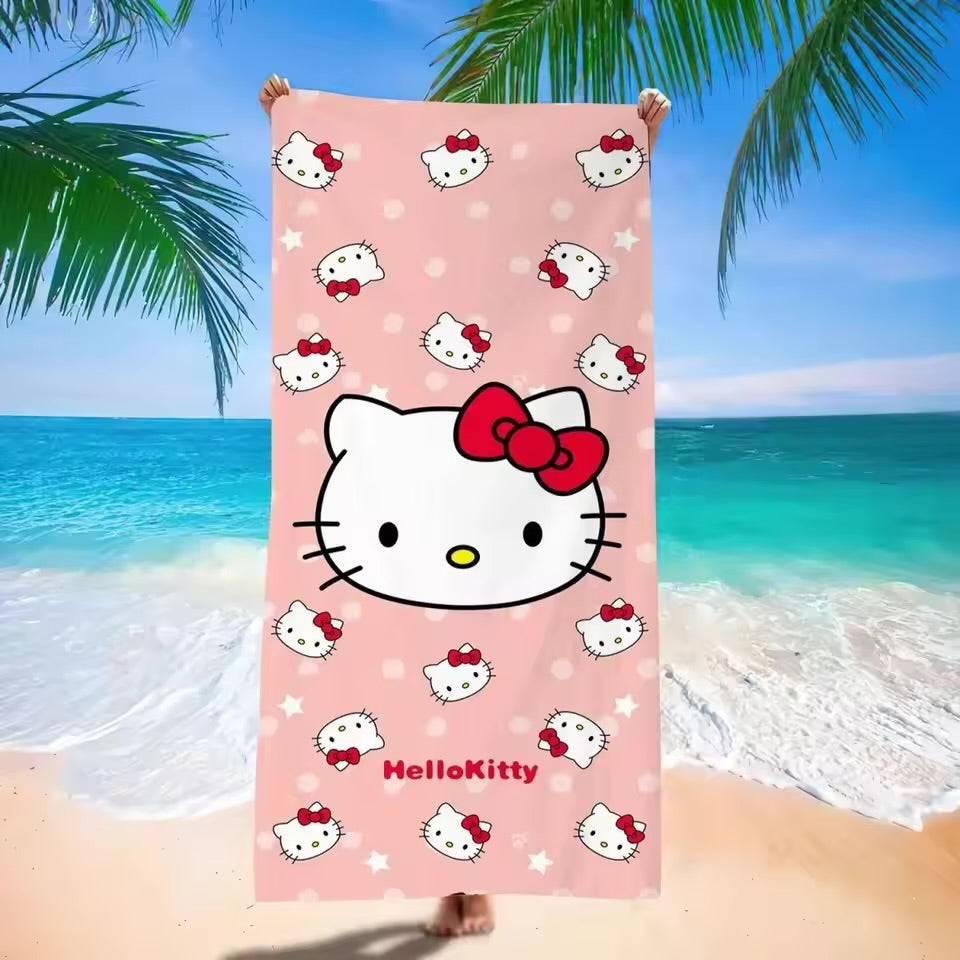 Hello Kitty beach towel on a sandy beach with ocean and palm trees in the background