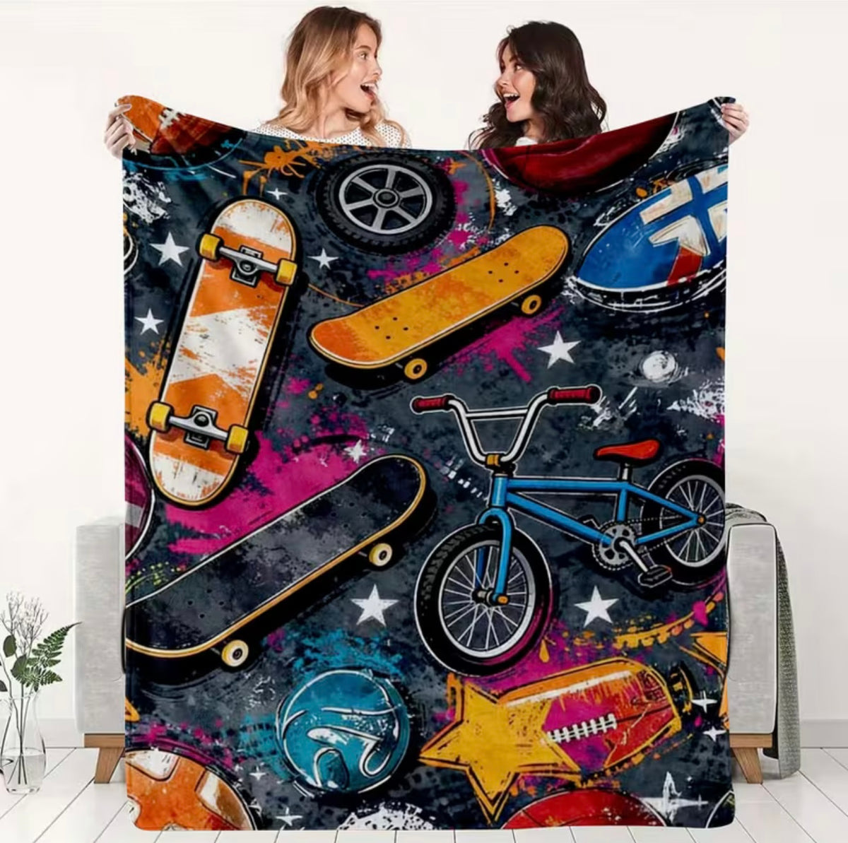 Two people holding a colorful blanket with skateboards, bikes, and other items on a white background