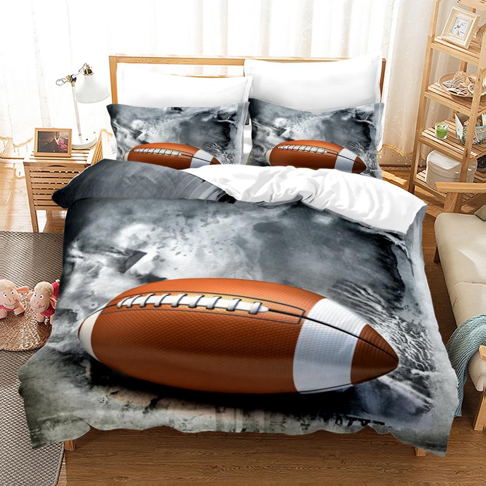 A bedding set displayed on a bed in a bedroom setting, featuring a large brown and white American football graphic over a smoky gray and black background, with matching pillowcases.