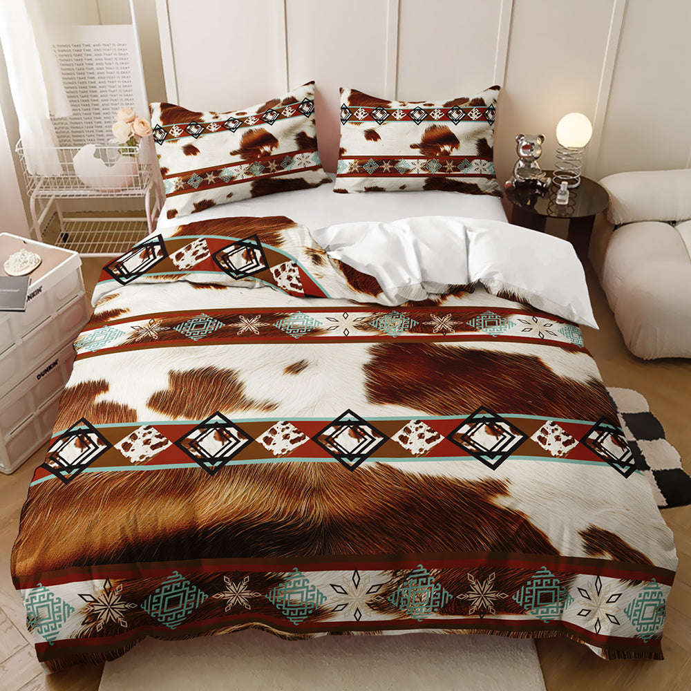 A made bed in a styled bedroom setting featuring a cowhide-inspired bedding set with brown and white patches, geometric Southwestern-style diamond motifs in black, teal, and cream, and matching pillow shams.