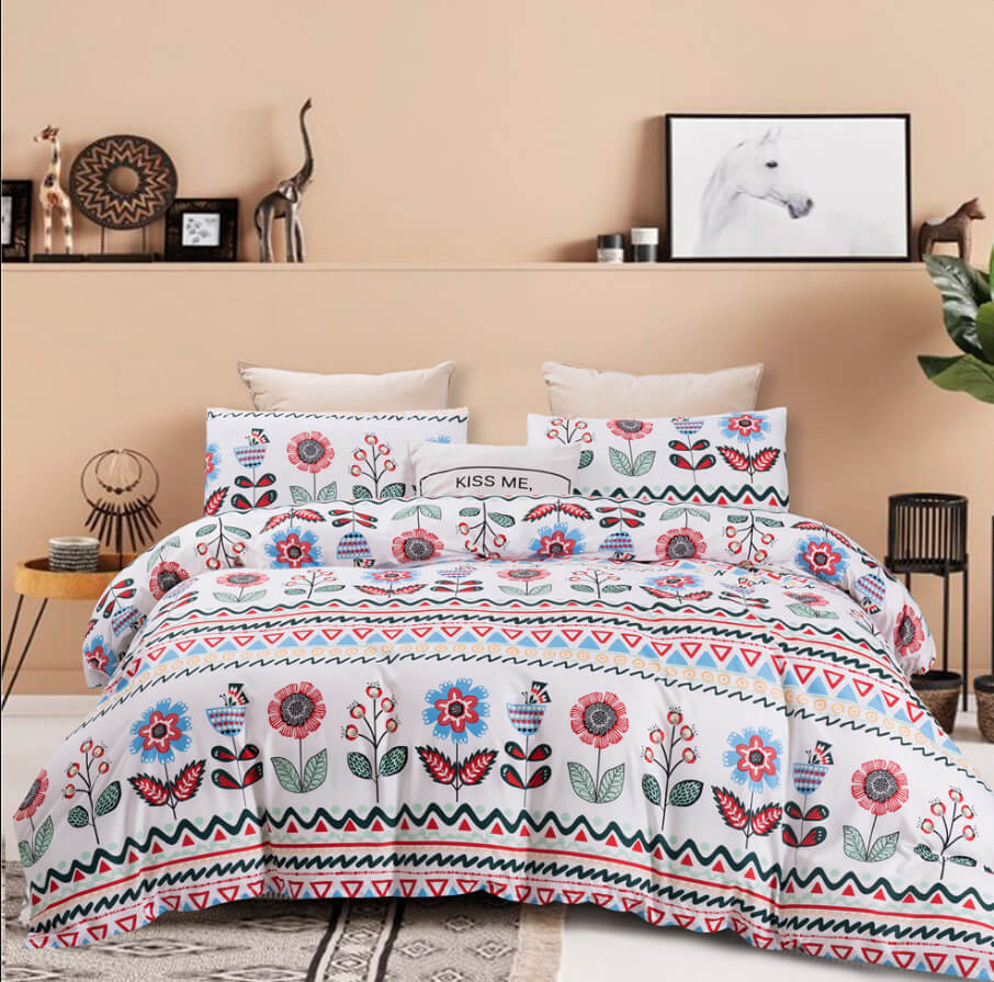 A bed dressed in a white comforter set with a colorful floral and geometric Southwestern-style print, styled in a warm beige bedroom