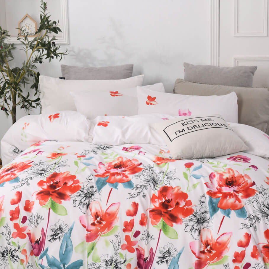 A bed dressed in a white floral duvet cover and matching pillowcases, styled