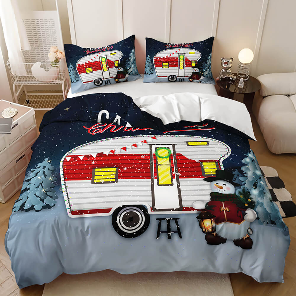 A Christmas-themed bedding set displayed on a bed in a bedroom setting. The set includes a duvet cover and two matching pillowcases featuring a large red and white retro camper trailer, a snowman, pine trees, and a snowy night sky.