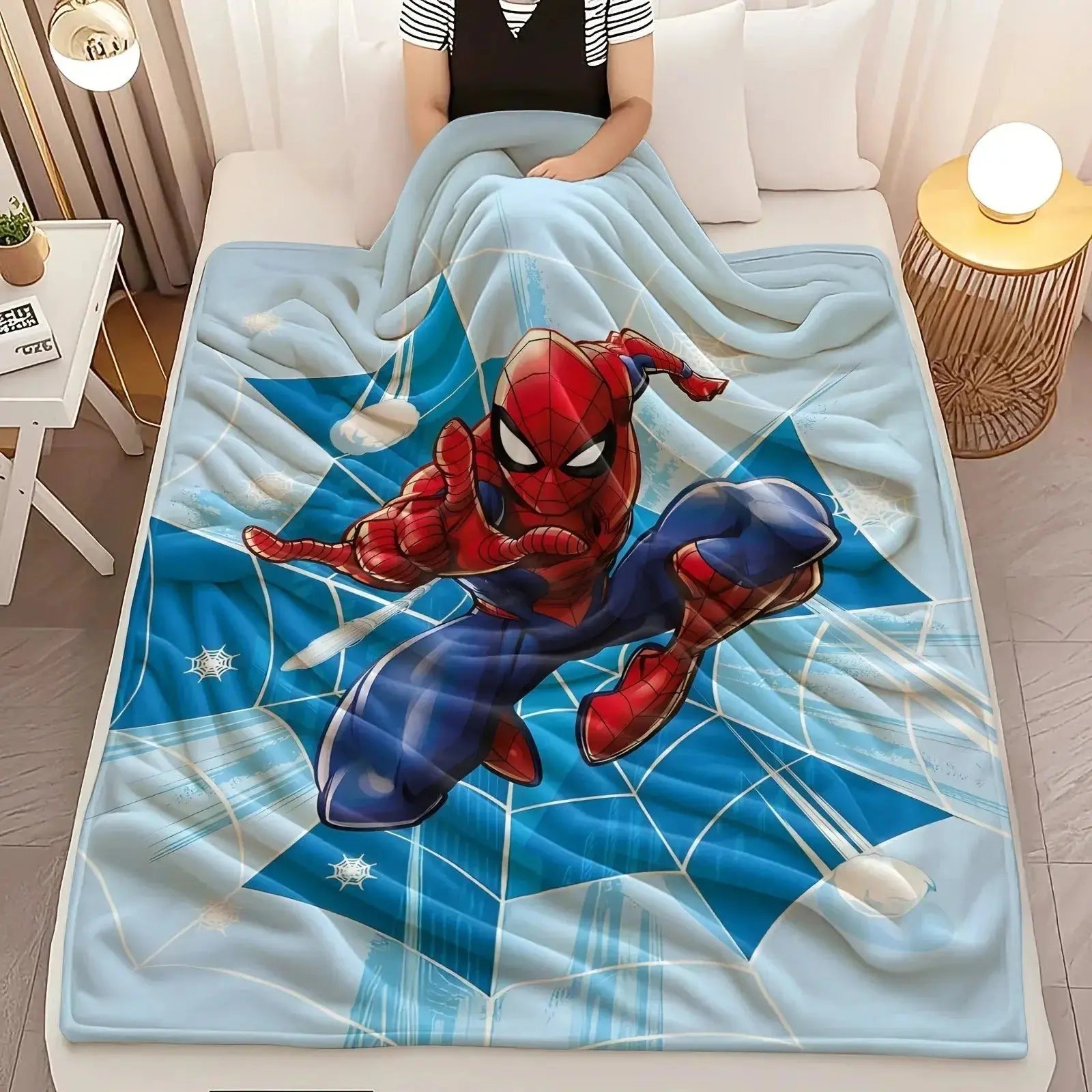 Spider-Man blanket laid on a bed with matching superhero-themed pillow